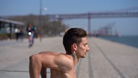 athletic bare-chested man training at riverside