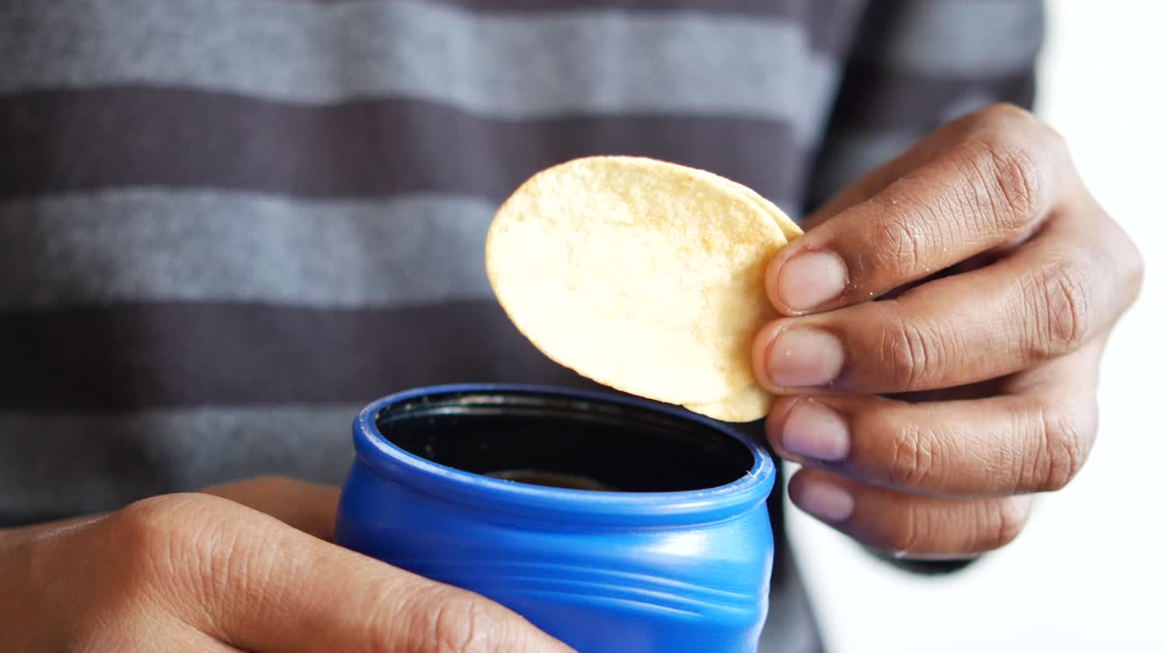 persona comiendo papas fritas de un recipiente azul
