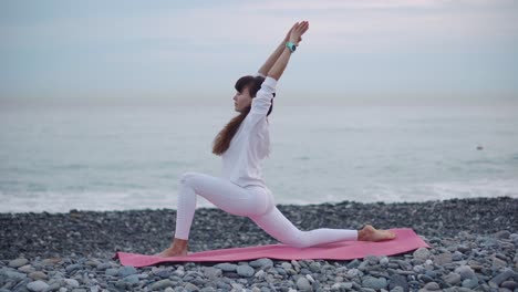 mujer practicando yoga en una playa al amanecer o al atardecer