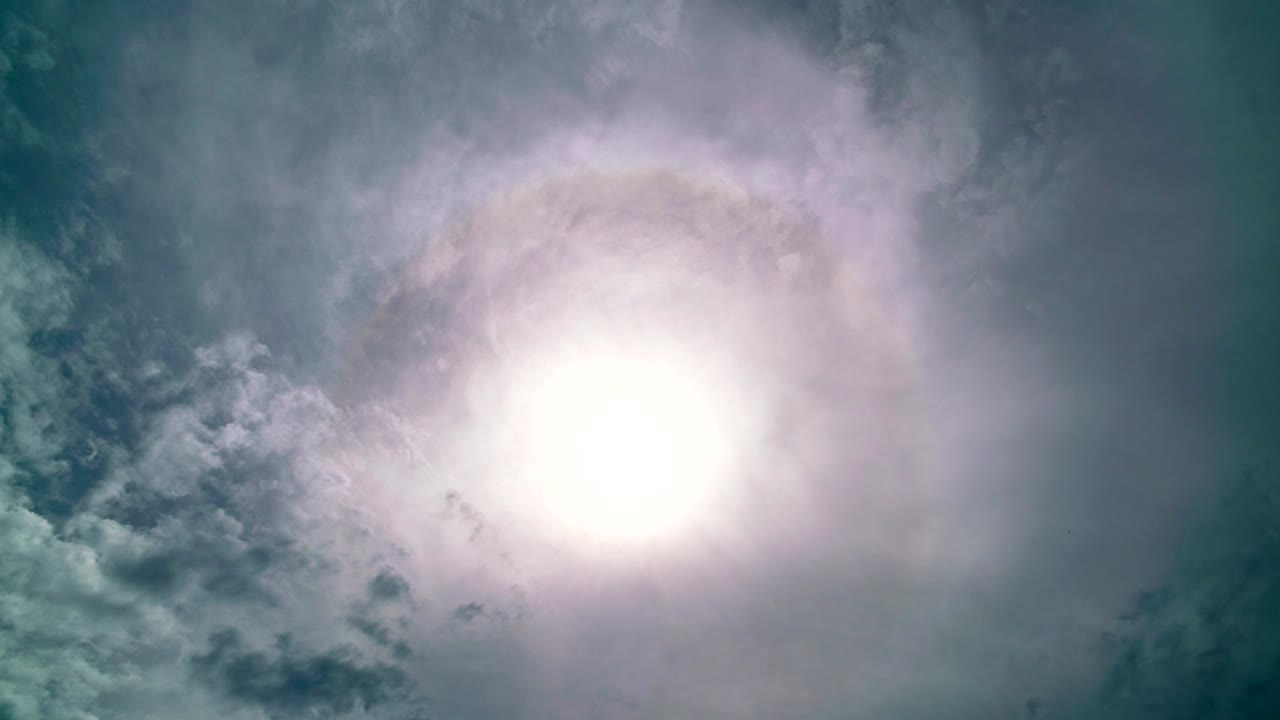 halo solar de 4k en el cielo azul nubes blancas, sol corona, fenómeno óptico, con destello de lente y nubes blancos que fluyen rápidamente en el cielo blue en un día de verano