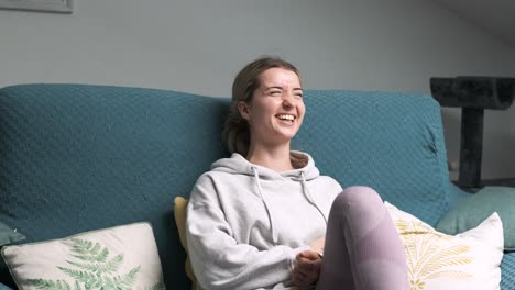 woman relaxing on sofa laughing at streaming service