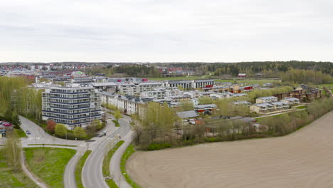 aerial, tracking, drone shot of a neighborhood, with apartment building and row houses, in a small town, cloudy, spring day, in viikki, finland