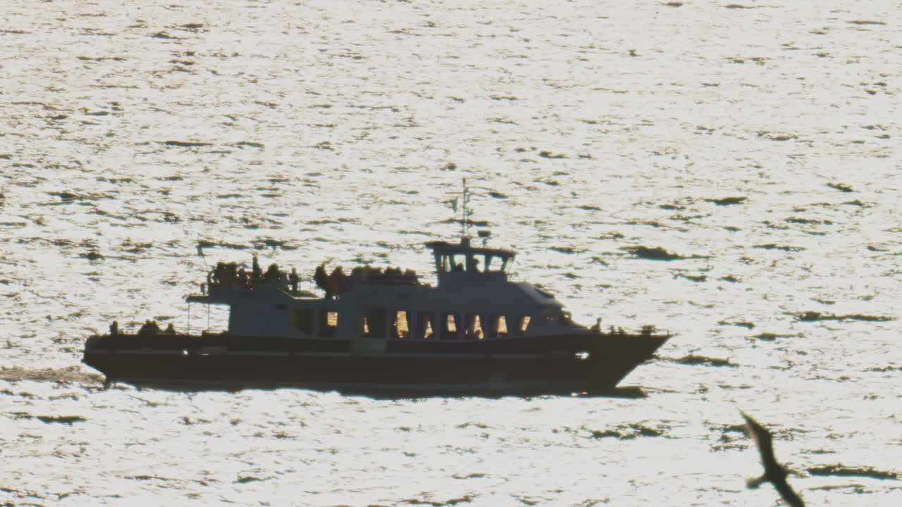 Blurred view of a boat filled with people moving on the sea on a sunny day
