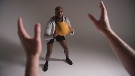 Foto-De-Estudio-De-Un-Jugador-De-Baloncesto-Masculino-Regateando-Y-Pasando-El-Balón-A-Su-Compañero-De-Equipo