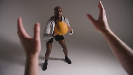 studio shot of male basketball player dribbling and passing ball to team mate