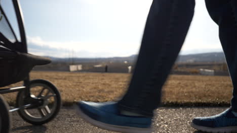 ground level view of a mother pushing a stroller by - feet and wheels only