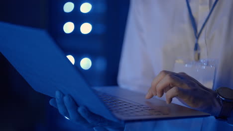 ritratto facciale di un uomo che lavora nella sala server con un laptop. tecnico che fa un controllo nella sala server. ingegnere caucasico che indossa una giacca grigia