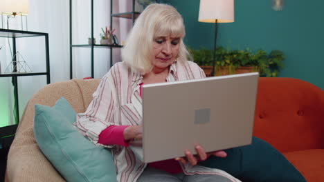 Senior-old-grandparent-starts-working-on-laptop,-sends-messages,-makes-online-purchases-at-home