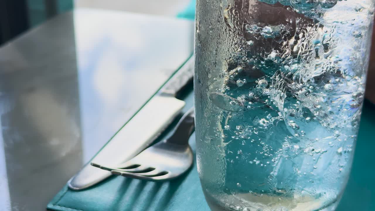 클럽 소다 거품이 유리잔에 상승하는 매크로 뷰, 자연 빛에서 식탁과 식구에 맞춰 설정