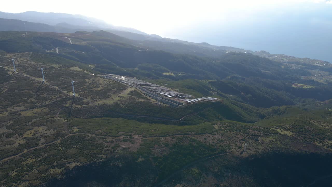 vista aérea de una granja fotovoltaica y una granja eólica en la cima de una montaña en la isla de paul da serra madeira