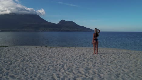 attractive woman stands on white island at camiguin during bright sunrise