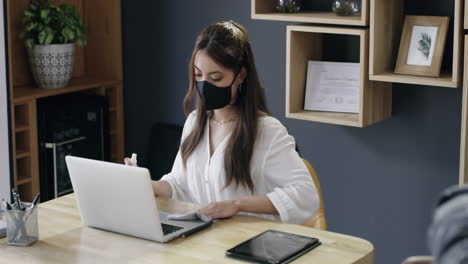 woman sanitizing hands in a home office setting during covid-19