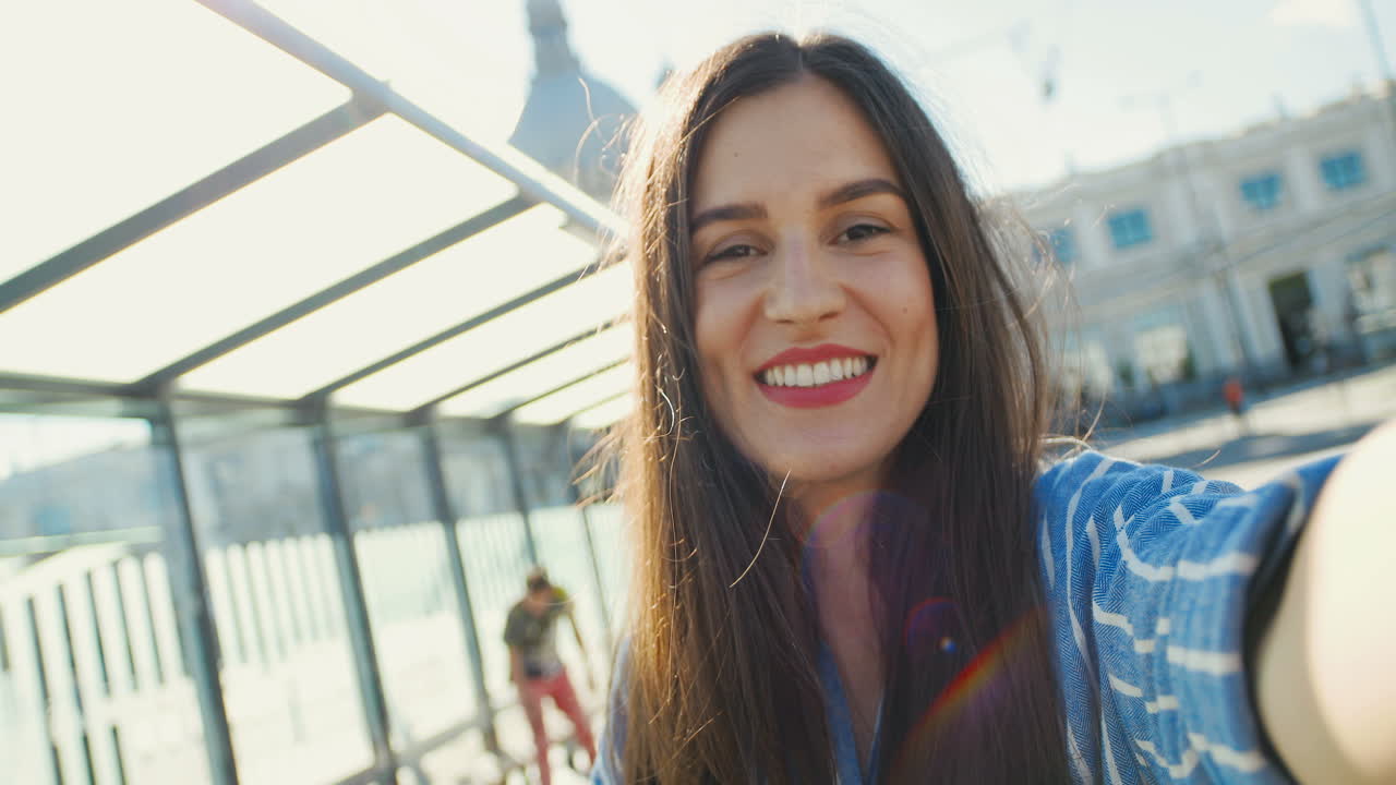 vista de cerca de una joven viajera feliz caucásica hablando, agitando las manos y sonriendo a la cámara al aire libre en verano