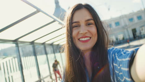 Close-up-view-of-Caucasian-young-happy-woman-traveller-talking,-waving-hands-and-smiling-at-the-camera-outdoors-in-summer