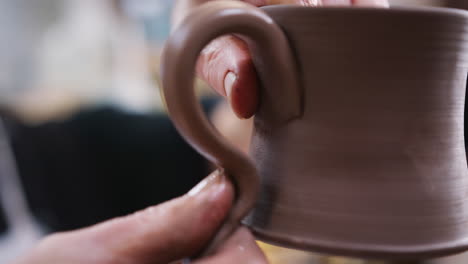 close up of male potter fitting clay handles to mugs in ceramics studio