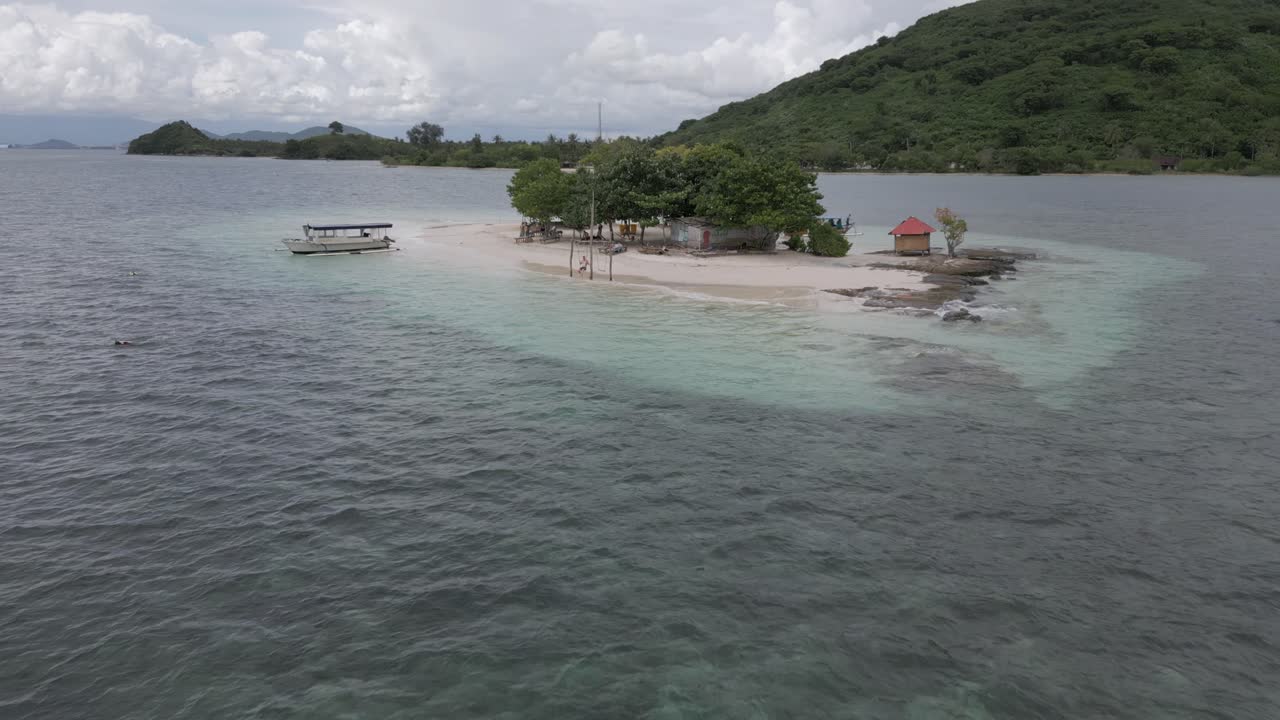 Un uomo si dondola su un'altalena da spiaggia su un piccolo isolotto sabbioso mentre il drone si allontana