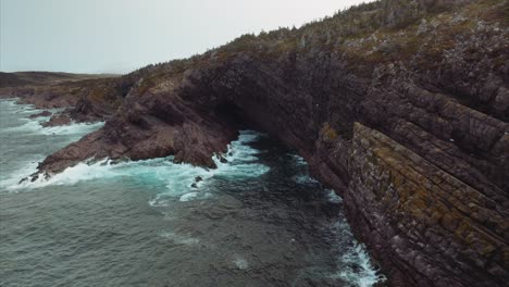 atlantic ocean waves crash against cliffs lining the coast and create foaming white surf as sea birds fly along the edge and over the sea