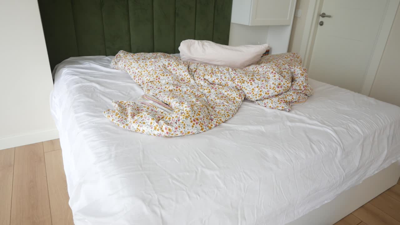 cama sin hacer con ropa de cama floral y almohadas