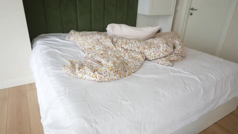 unmade bed with floral bedding and pillows