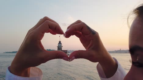 slow motion:beautiful girl makes heart shape with view of maiden tower inside in istanbul, turkey