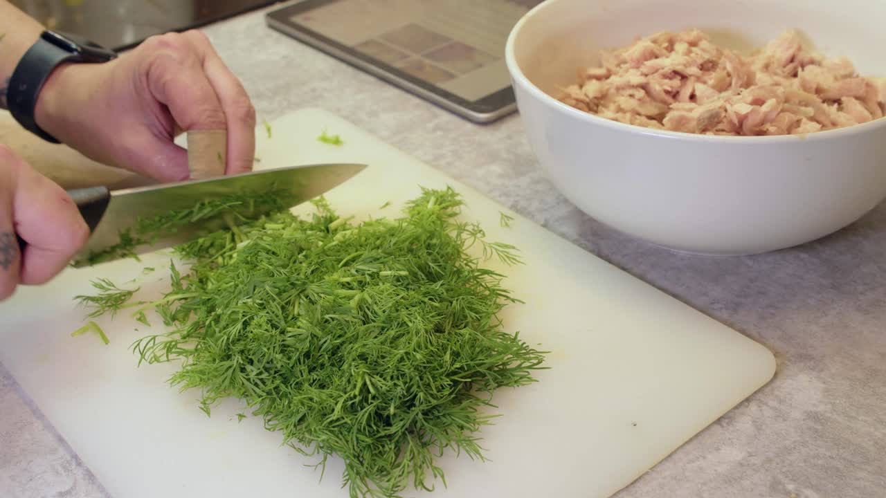 Man Chopping Fresh Dill for Chicken Dish