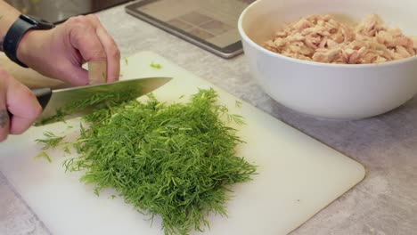 man chopping fresh dill for chicken dish