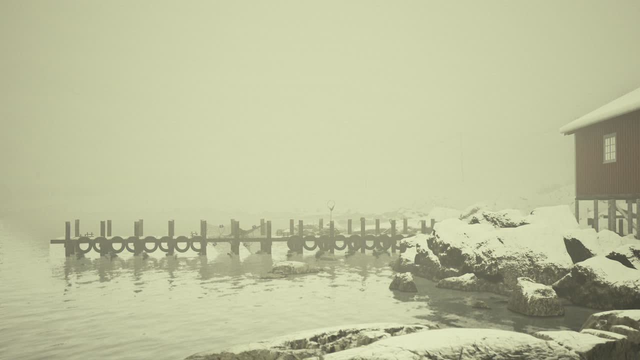 Snowy fishing pier surrounded by misty water on a cold winter day