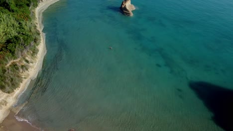 Vista-Aérea-De-La-Isla-De-Corfú-De-La-Costa-Con-Bosque-De-Pinos-Y-Una-Impresionante-Playa-Blanca-Solitaria