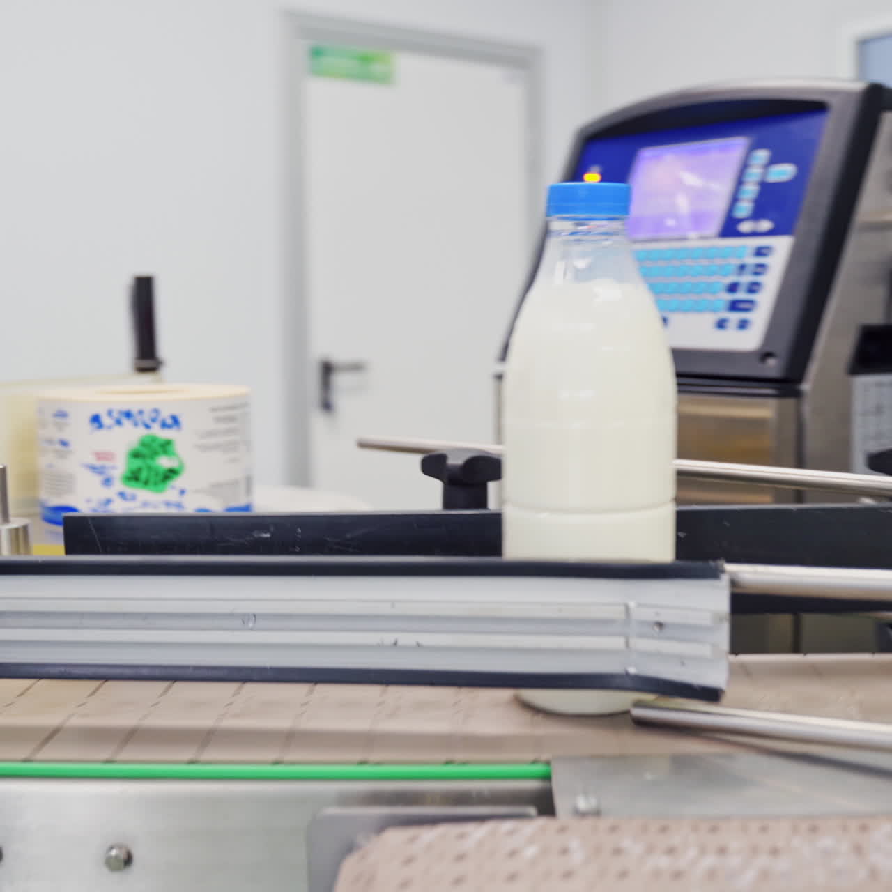 Modernized milk plant indoors. Worker is putting empty plastic bottles on a conveyor belt. Robotic machine for pouring milk in a dairy company.