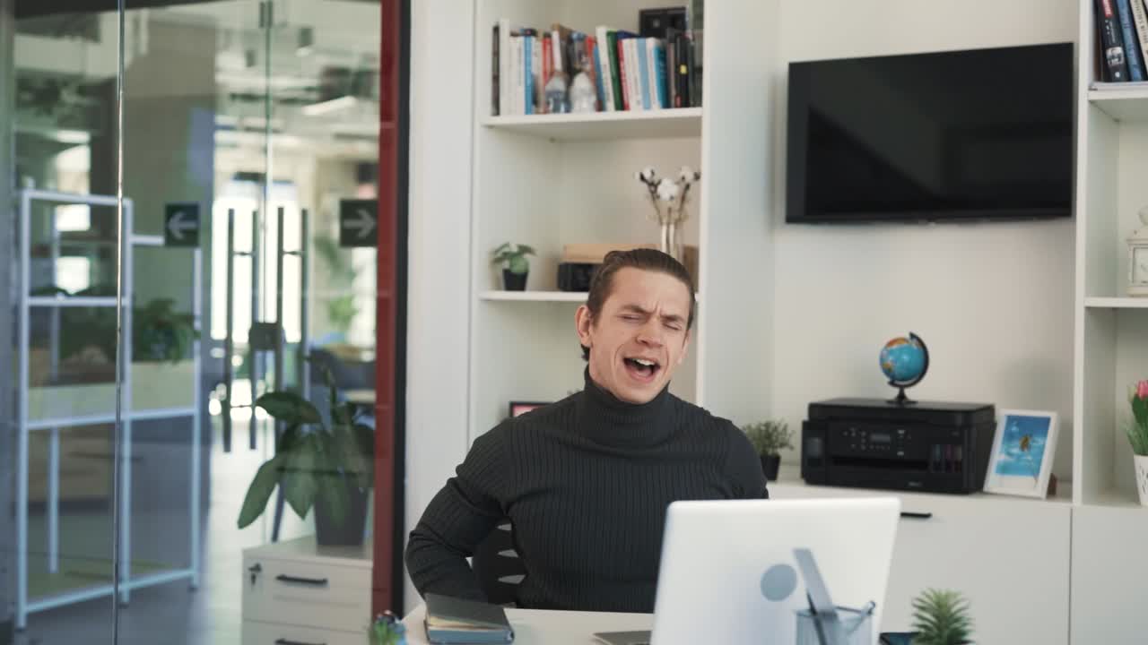 Il giovane atletico è seduto alla sua scrivania in ufficio, lavorando al suo laptop.