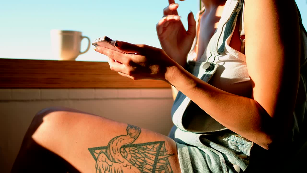 창문 근처에 앉아 휴대전화 4k를 사용하는 여성