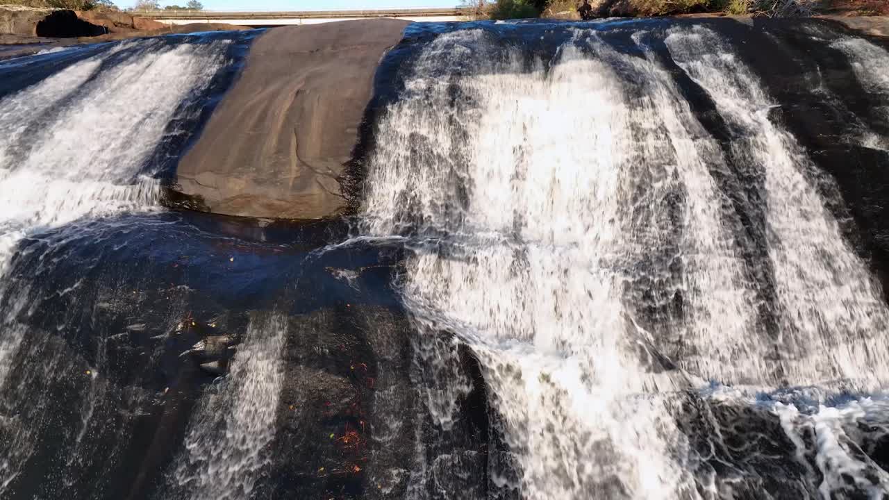 Water running on stone river at highfalls park GA with bridge on the back and transit