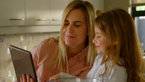 Mother-and-daughter-using-digital-tablet-while-preparing-food-4k