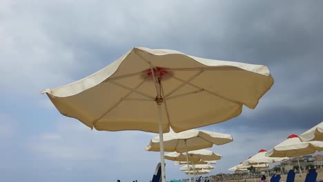 Sunshade-umbrella-at-the-beach-on-a-windy-cloudy-day