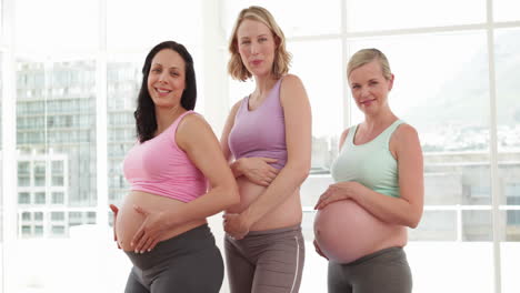 Pregnant-women-smiling-at-camera-in-fitness-studio