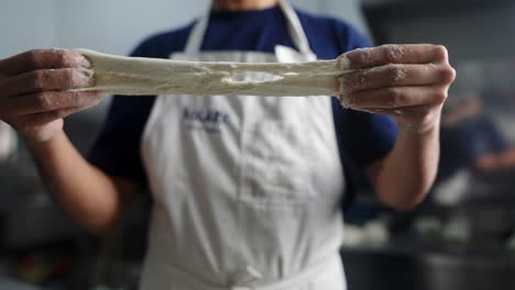 close up view in slow motion of a chef splitting wet pizza dough under cinematic and beautiful lighting