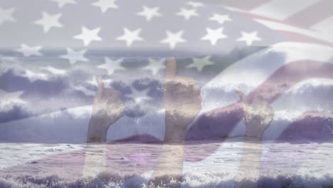 digital composition of waving us flag over hands showing thumbs up against waves in the sea