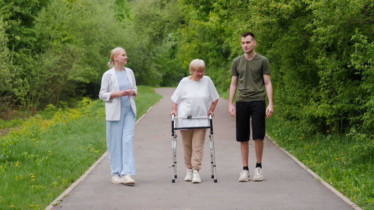 Elderly woman with walker being assisted by caretakers in a park