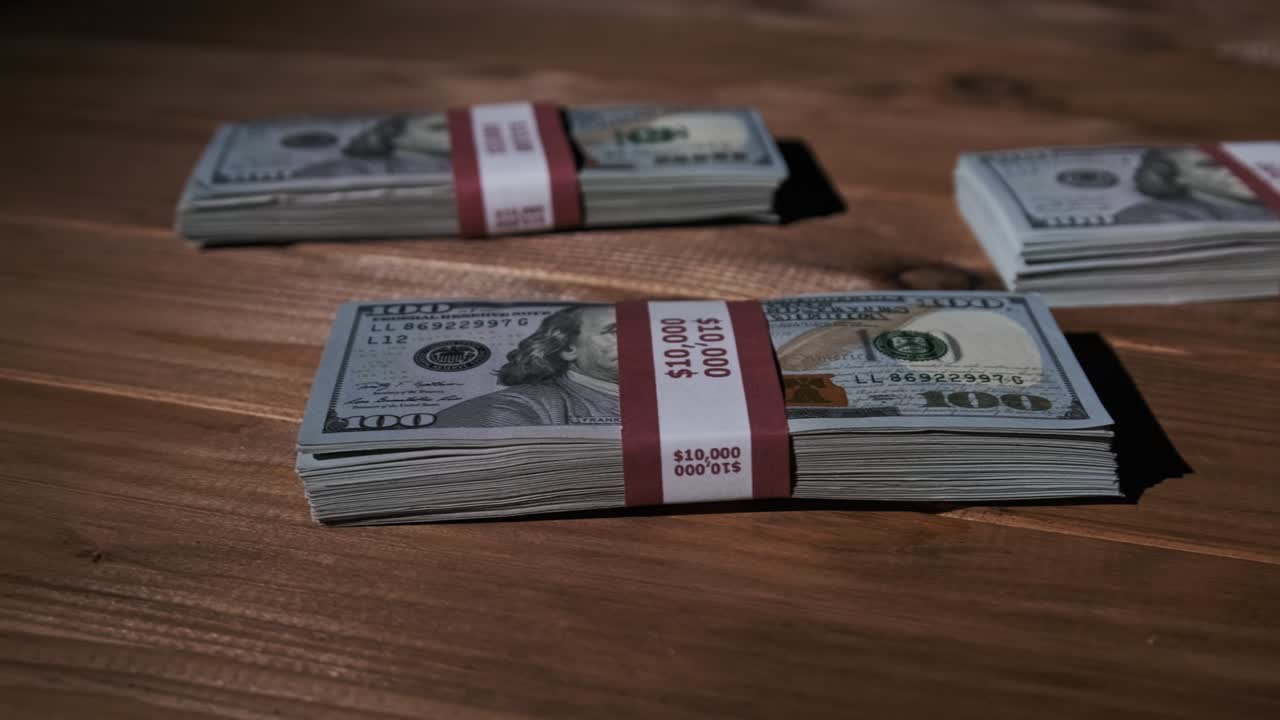 Three Stacks of 10000 American Dollars Banknotes in Bundles Lie on Wooden Table