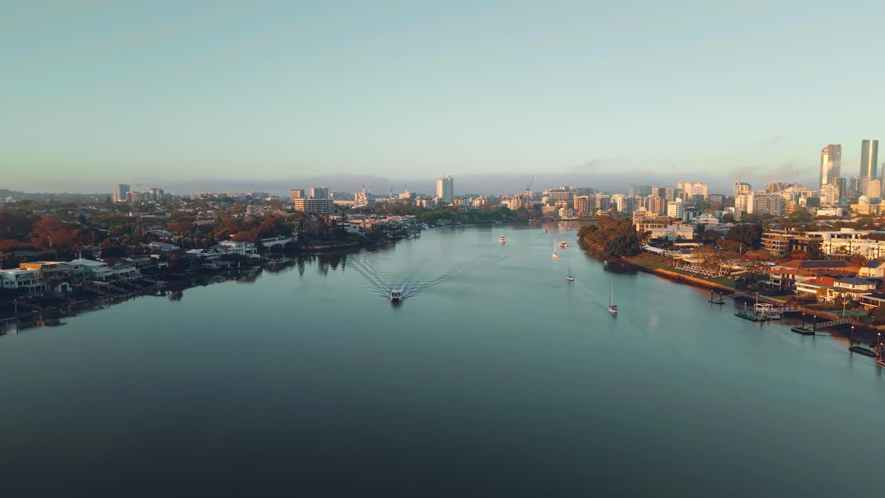 Panoramica aerea di una barca sul fiume Brisbane attraverso i sobborghi del centro città durante l'ora d'oro, CBD Teneriffe Brisbane Queensland Australia
