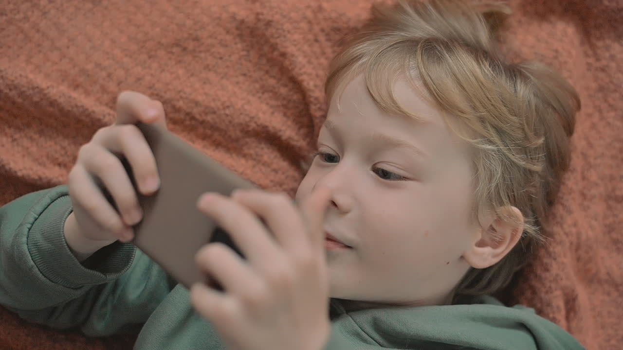 Portrait Of Little Boy Using A Smartphone Watching A Video
