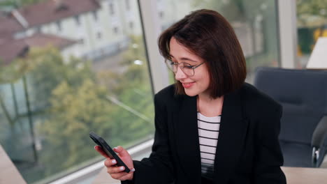 lovely positive caucasian woman looks at her smartphone. high angle view on the lady using gadget. blurred backdrop.