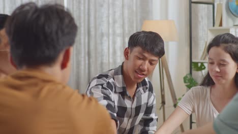 close up of asian teen group sitting and discussing at home. putting their hands together as a symbol of teamwork, screaming celebrating