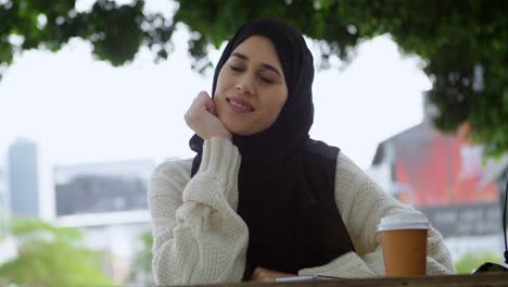 woman in hijab relaxing at outdoor cafe 4k