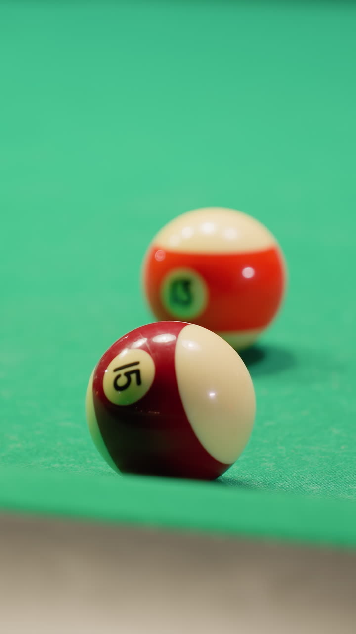 White billiard ball rolls across green pool table after making contact with another ball. Vibrant pool balls scattered across surface capture dynamic motion of gameplay, showcasing precision