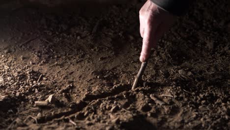 Hand-writing-in-the-dust-with-a-stick-medium-shot