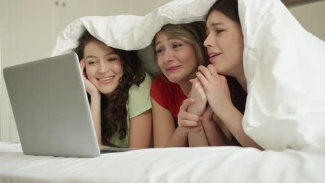 three best friend woman on bed watching lovestory on laptop together