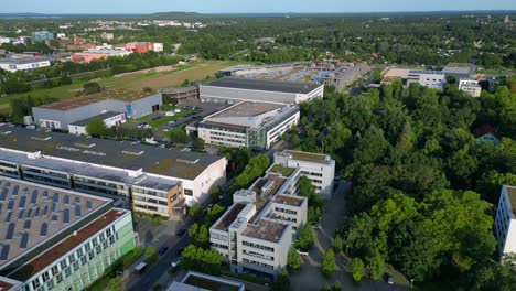 modern film studios with offices and sound stages surrounded by trees in berlin adlershof, germany. dramatic aerial view flight overflight flyover drone