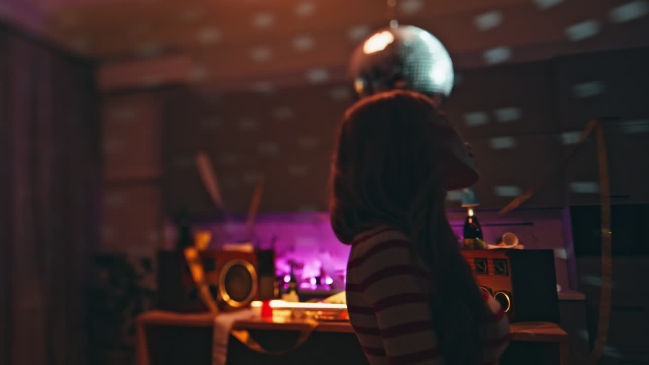 Relaxed woman dancing alone under disco ball in empty apartment close up.