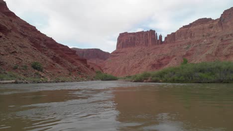 a river flows through a desert canyon with towering red rock formations